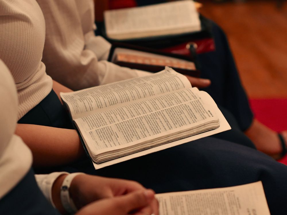 Three persons holding Bibles on their lap